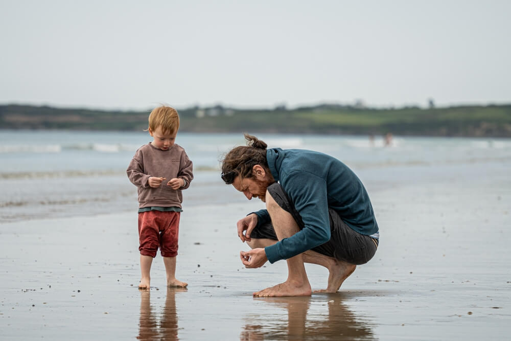 A parent and their child looking for shells on an Ocean Shores beach.