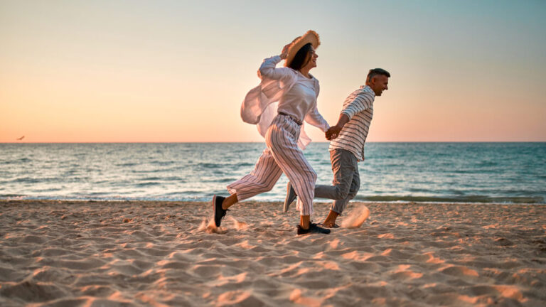A couple running on the beach on one of their romantic weekend getaways in Ocean Shores, Washington.